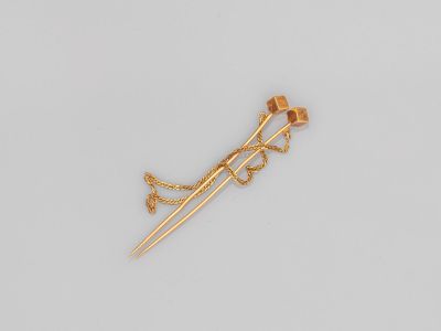une photo d'une broche plaquée or, avec une chaîne et une fleur