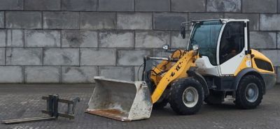 une photo d'un petit engin de chantier garé devant un mur