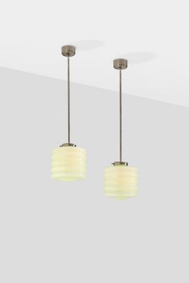 a pair of white glass pendant lights hanging from a ceiling