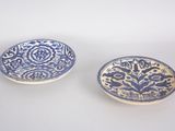 pair of blue and white plates with designs on them on a white surface