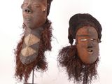 pair of african masks on stands on a white background