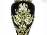 un vase noir orné d'un motif vert et blanc