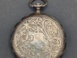 an antique silver pocket watch with a floral design on the face