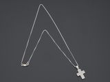 un collier avec une croix en argent et une longue chaîne, sur fond sombre