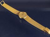an image of a gold wrist watch on a blue surface