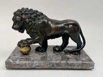 statue d'un lion posée sur un socle en marbre, tenant une boule entre ses pattes