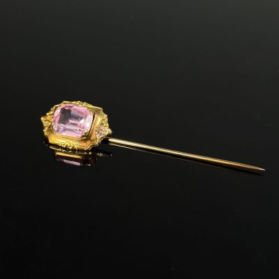 a gold and pink stone broochle pin on a black surface