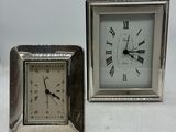 une petite horloge en argent posée à côté d'une autre horloge en argent, plus petite