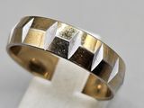 gros plan d'une bague en or et en argent sur une surface blanche