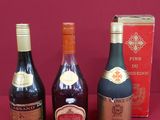 four bottles of wine are lined up on a red surface