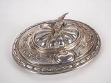 a silver plate with a bird on it on a white surface