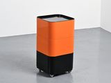 an orange and black trash can sitting on top of a cement floor