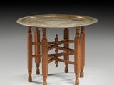 une table dont le plateau est en laiton, avec des pieds et un piètement en bois