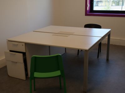 a white table with a green chair in front of it