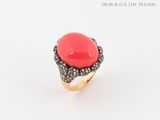 une photo d'une bague en corail et diamants sur fond blanc