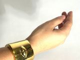 la main d'une femme tenant un bracelet en or orné d'un crâne