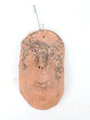 Visage stylisé en terre cuite. H.