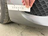 a person holding a measuring tape on the front of a car