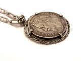silver coin with a chain attached to it on a white surface
