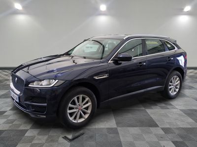 un SUV Jaguar bleu garé dans un showroom au sol carrelé