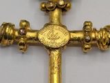 a gold cross with a coin on top of it