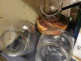 three empty glass jars on a shelf in a kitchen