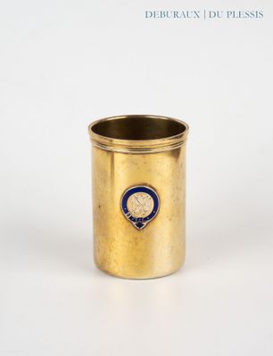 une coupe en or ornée d'un emblème bleu, posée sur une surface blanche