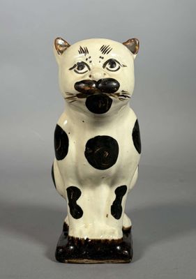 une figurine de chat noir et blanc posée sur une surface grise