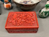 a red box sitting on a table next to other vases