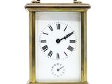 une petite horloge en laiton avec des chiffres romains sur le cadran