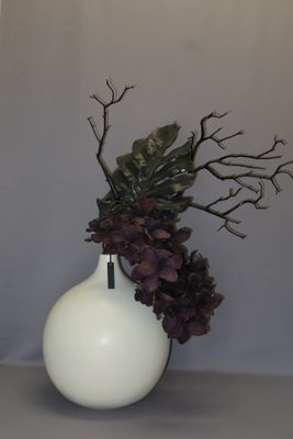 a white vase with a plant in it on a table