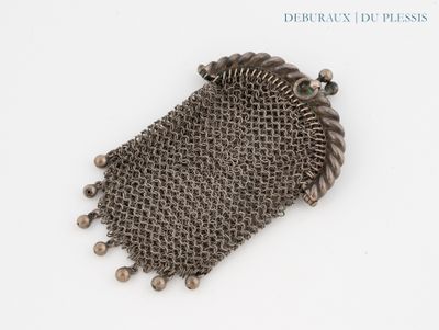 un gros plan d'un sac à main en cotte de mailles posé sur une surface blanche
