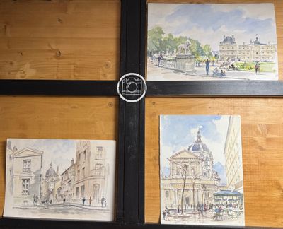 quatre tableaux accrochés au mur d'un immeuble, photographiés par un appareil photo