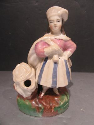 a figurine of a woman with a hat and a bag