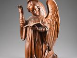 une statue ancienne en bois représentant un ange tenant un livre