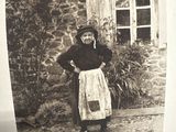 an old picture of a woman standing in front of a house