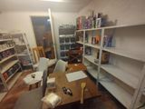 a room with a table, chairs, shelves, and other items