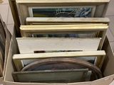une boîte remplie de photos encadrées, posée par terre dans un magasin