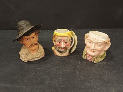 trois figurines en céramique représentant des hommes portant un chapeau et une barbe, posées sur un fond noir