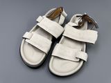 white leather sandals with straps on a gray surface