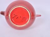 a red vase with a gold rim on a white surface