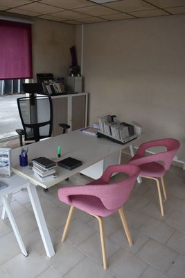 brightly colored chairs sit in front of a white table with a computer on it