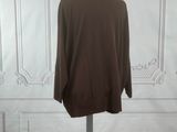 brown sweater on a mannequin stand in front of a white wall