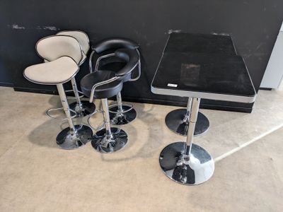 trois tabourets de bar noirs et blancs et une table dans une pièce