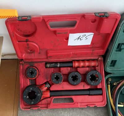 une boîte à outils rouge contenant des outils, posée par terre
