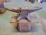 a metal anvil sitting on a wooden block in a workshop