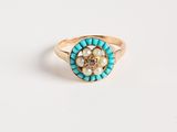 un gros plan d'une bague en or ornée de perles et d'une fleur