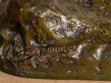 bronze statue of a dog on a rock on a table