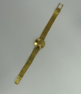a gold watch on a white surface with a white background