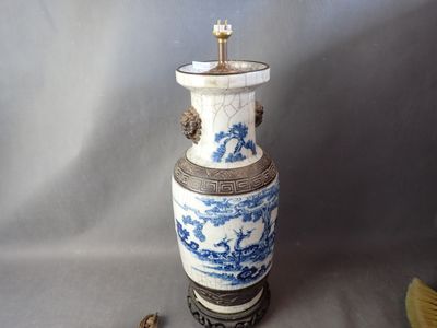 un vase bleu et blanc posé sur une table à côté d'un ventilateur